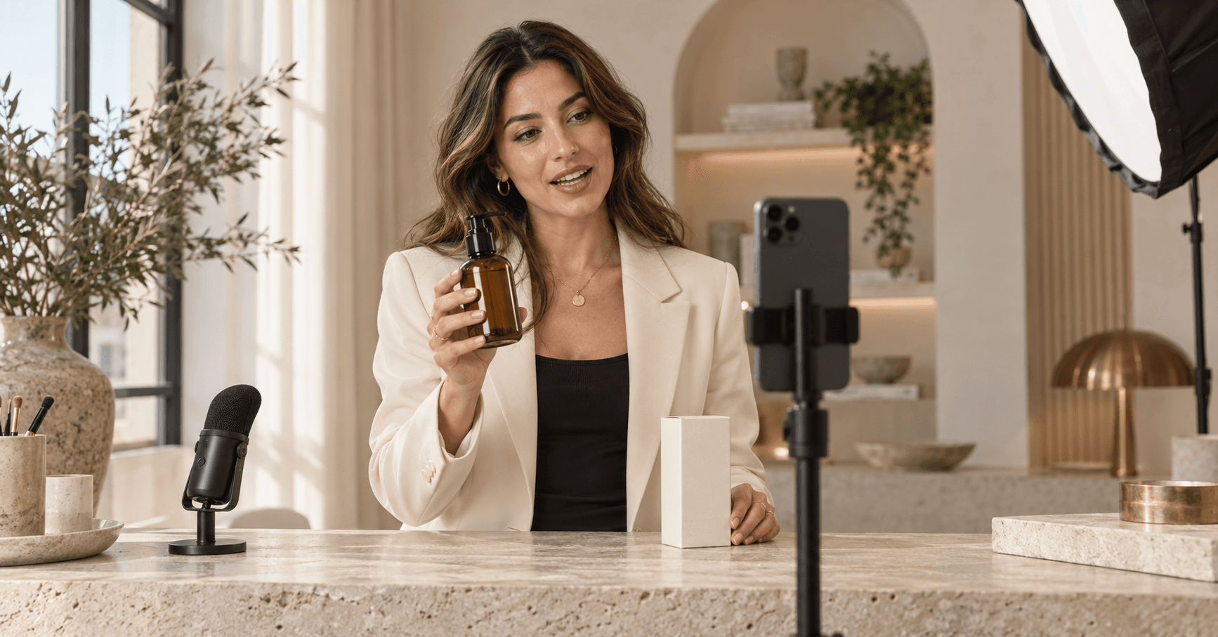Creatorin präsentiert ein Produkt vor einer Smartphone-Kamera in einem hellen Studio mit Mikrofon und professionellem Licht.